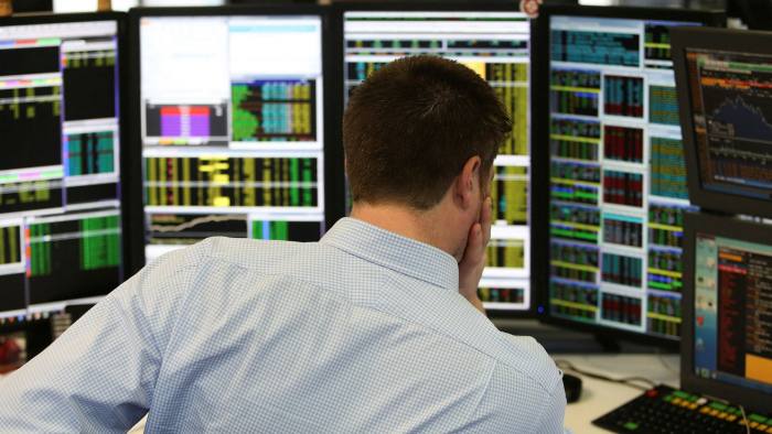 A trader monitors financial information on computer screens