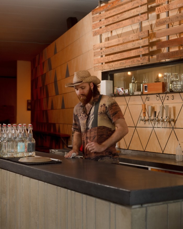 A bearded male bartender wearing a straw hat at Luppolo