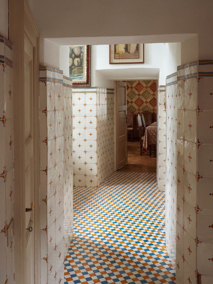 The hallway decorated with contrasting tiles on the walls and floor, leading through to the kitchen
