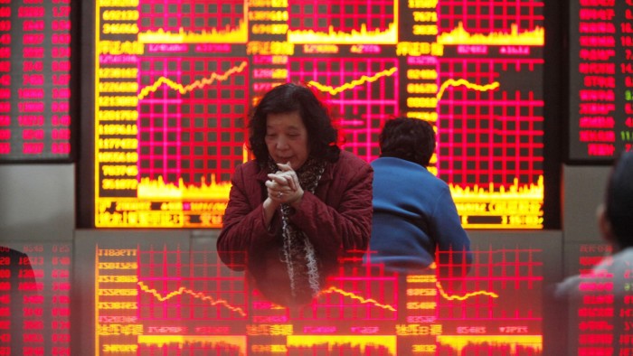 Investors in front of screen showing stock prices