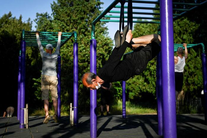 An elderly man exercises at a park