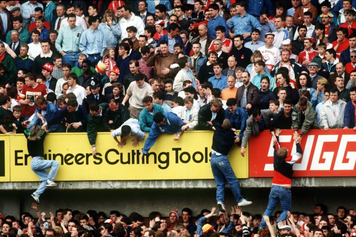 Fans are pulled to safety on to the upper tier amid the overcrowding disaster at Hillsborough stadium in 1989