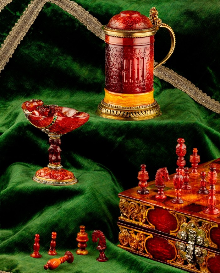 Elaborate amber objects such as a tankard and chess board and pieces on forest-green velvet