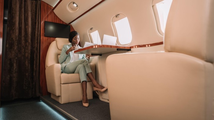 African-American businesswoman drinking coffee and reading newspaper inside a private jet
