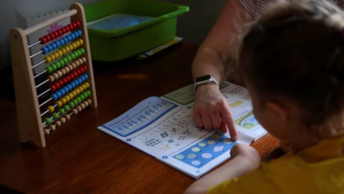 A four-year-old girl does maths work at home with her mother