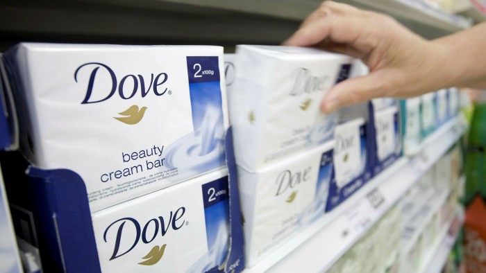 A Pprson reaches for Dove soap on a store shelf 