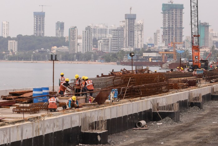 Labourers work at the coastal road construction site, in Mumbai, India