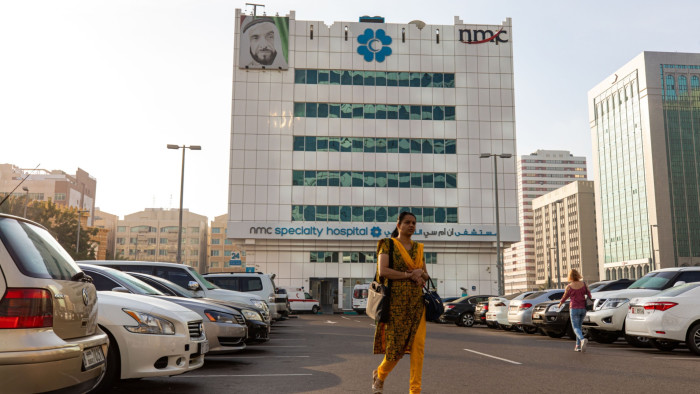 People walk through a car park outside the NMC Speciality Hospital, operated by NMC Health, in Dubai