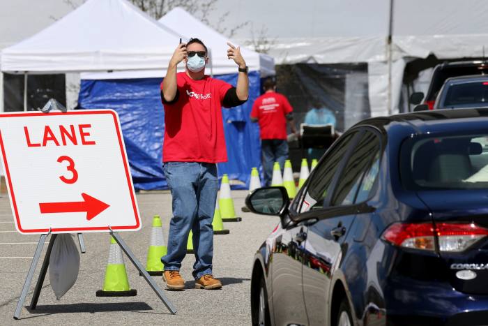 LOWELL, MA - APRIL 7: A man directs vehicles as they arrive at a rapid COVID-19 testing site in Lowell, MA on April 07, 2020.