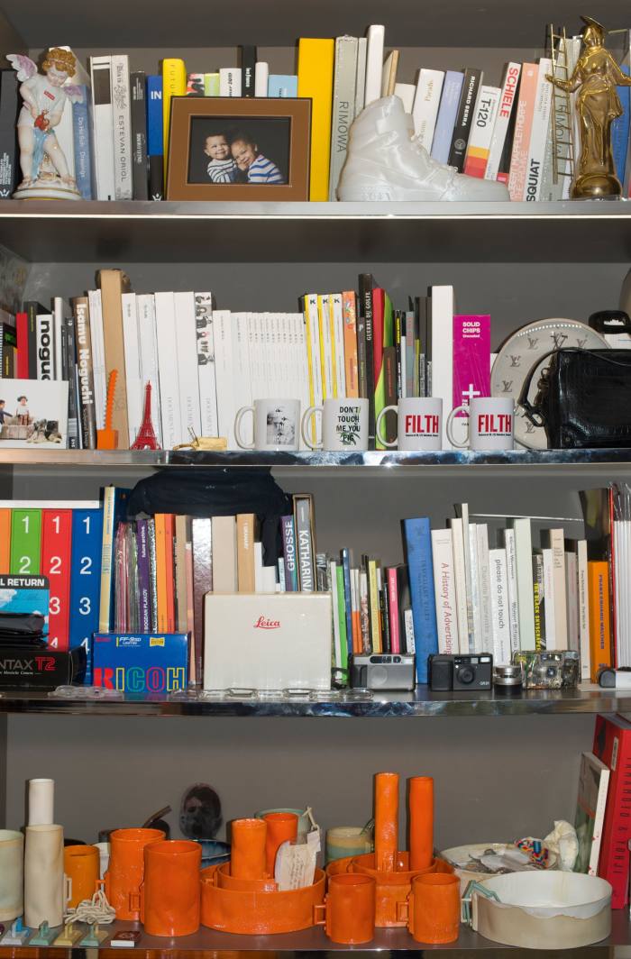 Virgil Abloh’s shelves make for an impressive CV. Each one boasts of his multi-disciplinary career interests, with references to Louis Vuitton, where he is artistic director of menswear, as well as nods to his own Off-White label. But he punctuates them with personal details designed to curtail any hubris: note the particular interest in pocket-sized cameras, family photos and kitsch religious curios