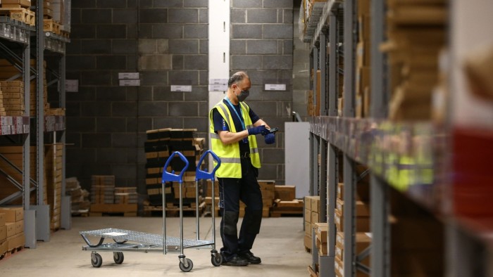An employee in a warehouse looking at a gadget on his forearm