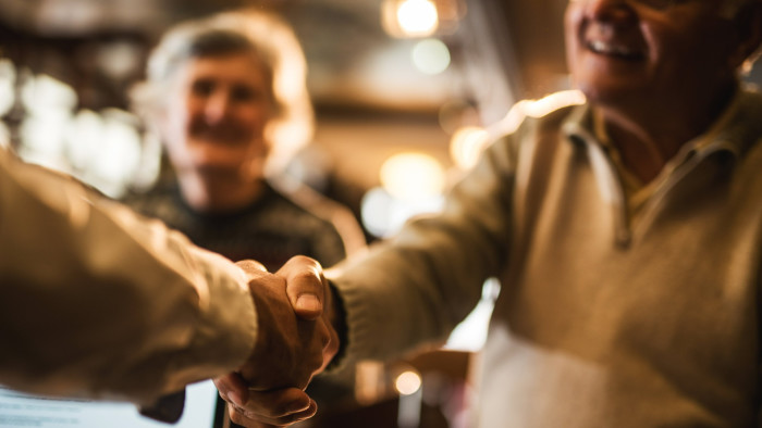 Close up of older people coming to an agreement with an insurance agent and shaking hands
