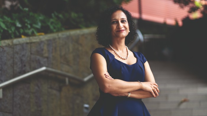 Essec professor Aarti Ramaswami, arms crossed, smilng with mouth closed looking at the camera