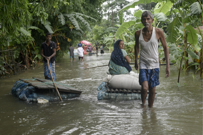 Flood-affected people carry rice bags on a raft