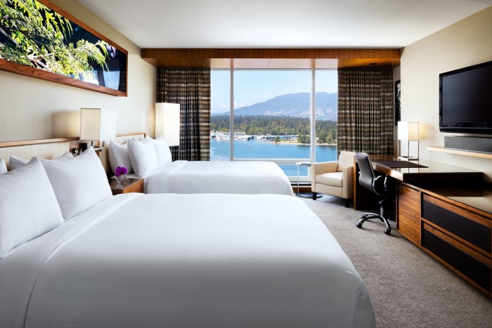 A guest room at the Fairmont Pacific Rim with a view of the harbour and mountains beyond