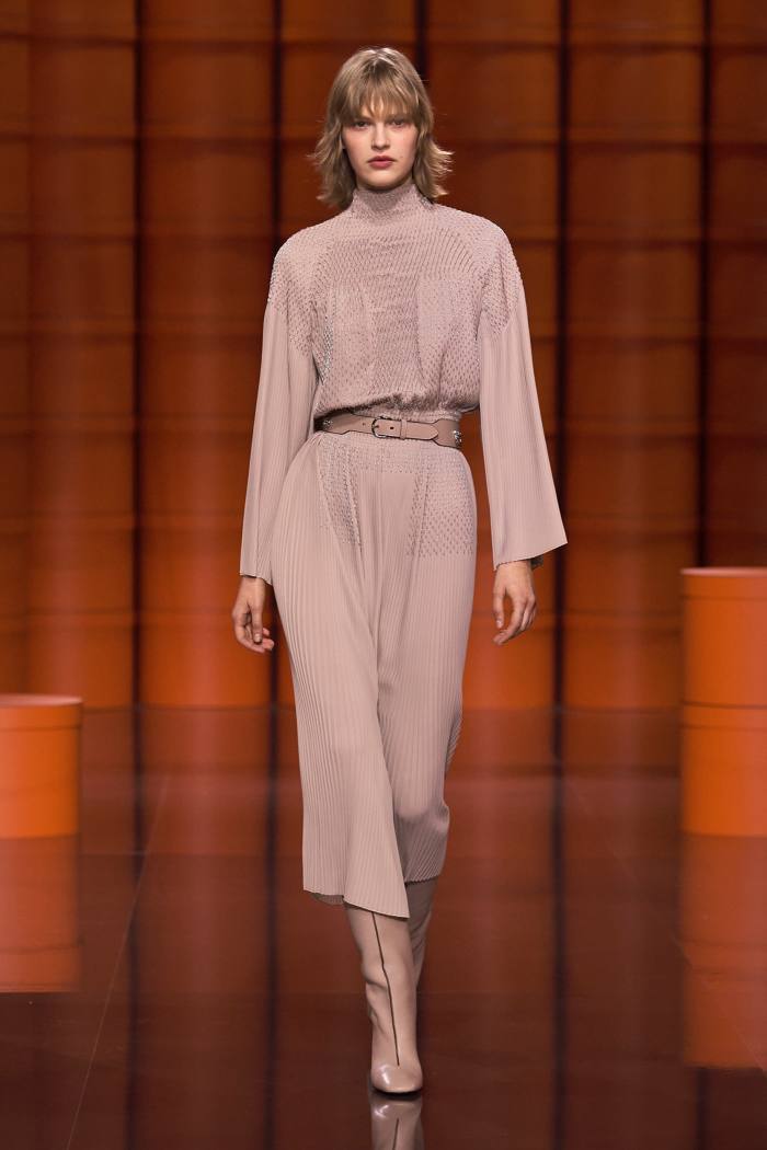 Hermès beige polyester georgette smocked plissé dress, Tadelakt calfskin belt, and calfskin boots from the house’s AW21/22 collection