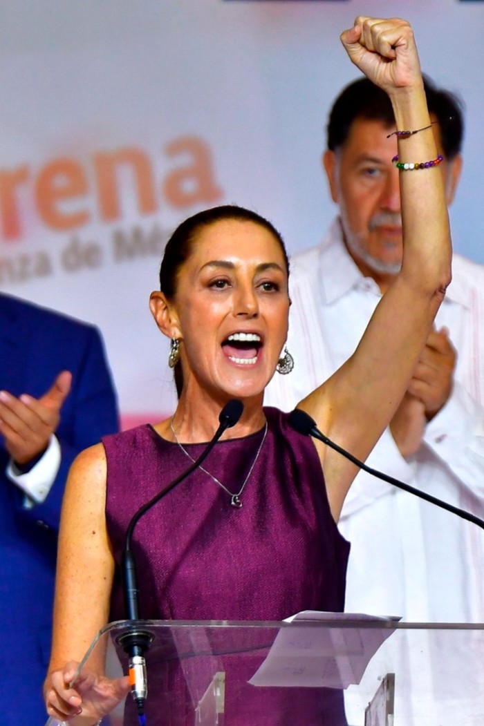 Woman speaking to a crowd withher arm raised high