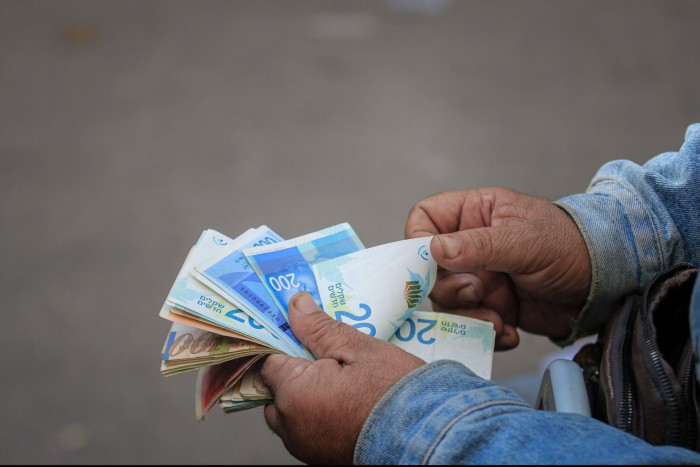 A man counts Israeli shekel banknotes