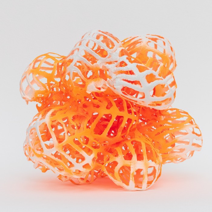 A small sculpture made from orange paper looking like hollow walnuts