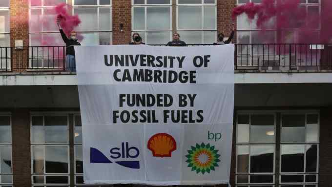 Protesters holding flares and a banner at Cambridge university’s engineering department in February 2023