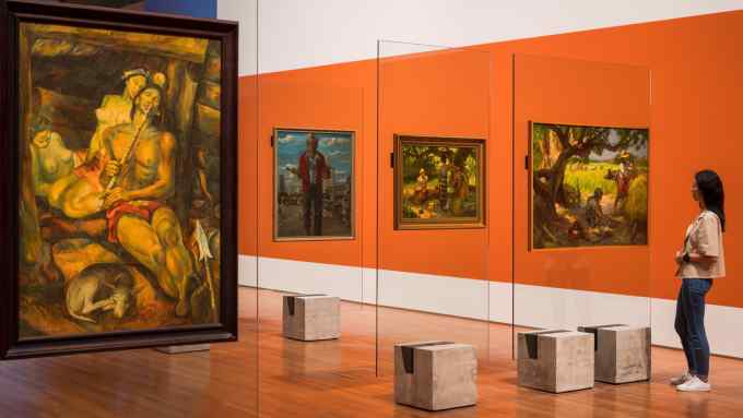 View of paintings hanging on glass walls in the middle of an orange gallery