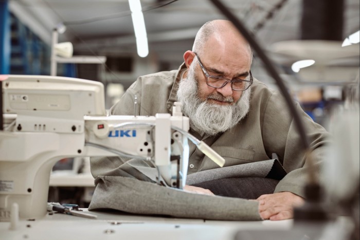 A man using a sewing machine to stitch some fabric