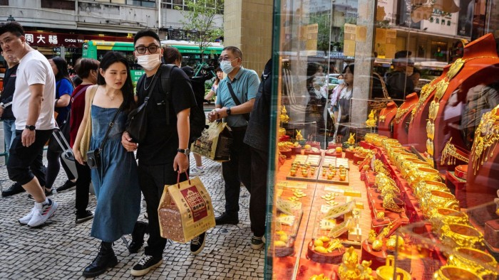 Pedestrians pass a gold display window at a jewellery store in Macau