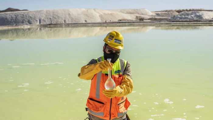 A mine worker takes water samples from a brine pool at a lithium mine in Chile
