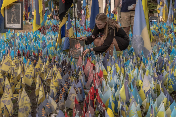 A woman holds a portrait of a Ukrainian soldier at a memorial area in Kyiv