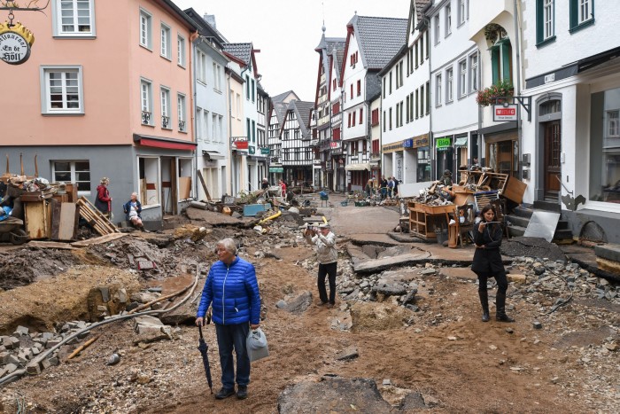 People walk through the debris in the pedestrian zone after a heavy rain