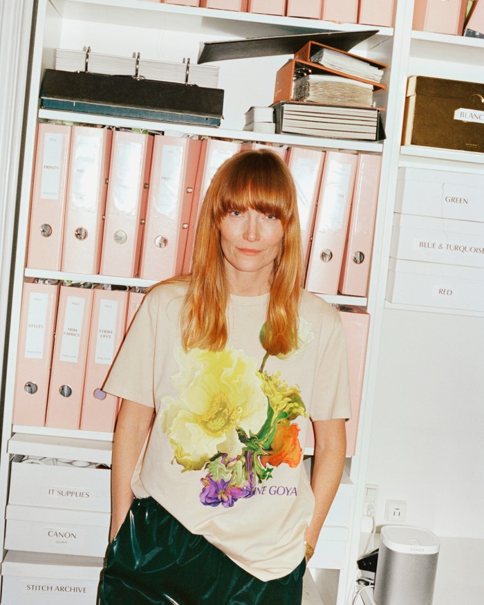 Stine Goya standing in front of shelving stacked with pink files and folders at her label’s Copenhagen headquarters