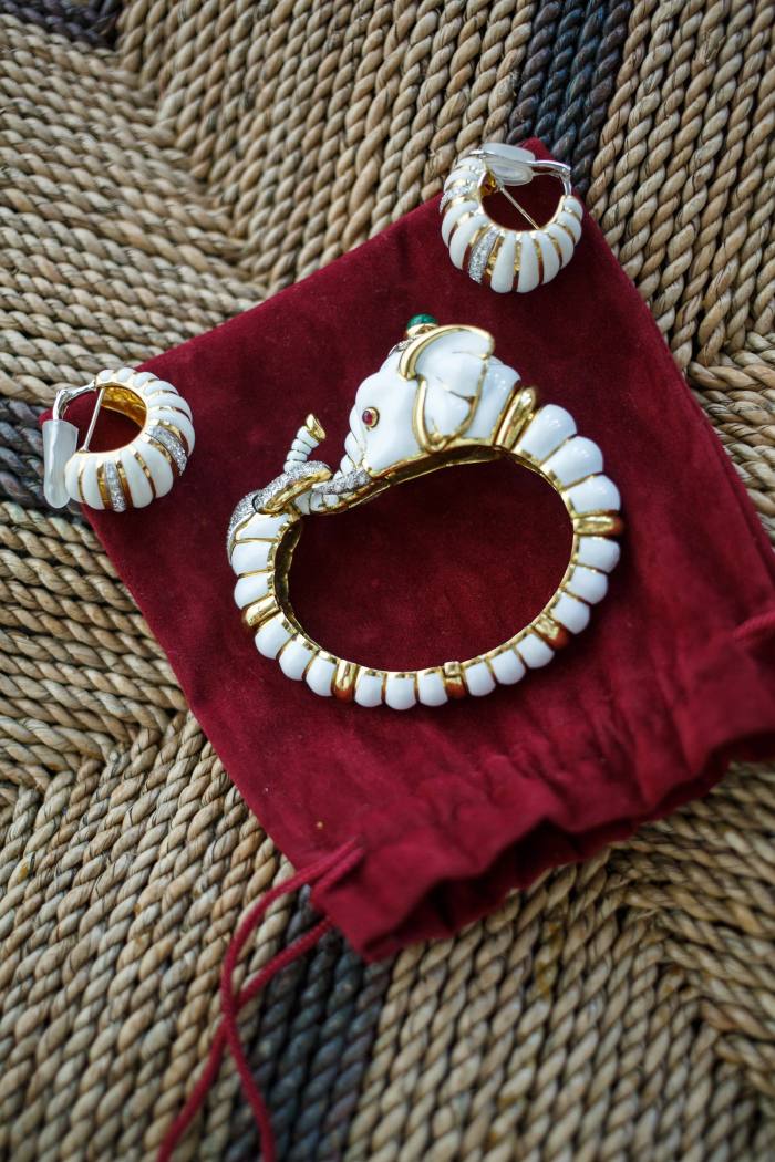A pair of white-and gold earrings and a bracelet on a red velvet bag