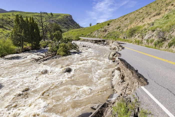 Water pours down a hillside as huge parts of the tarmacked road are literally washed away