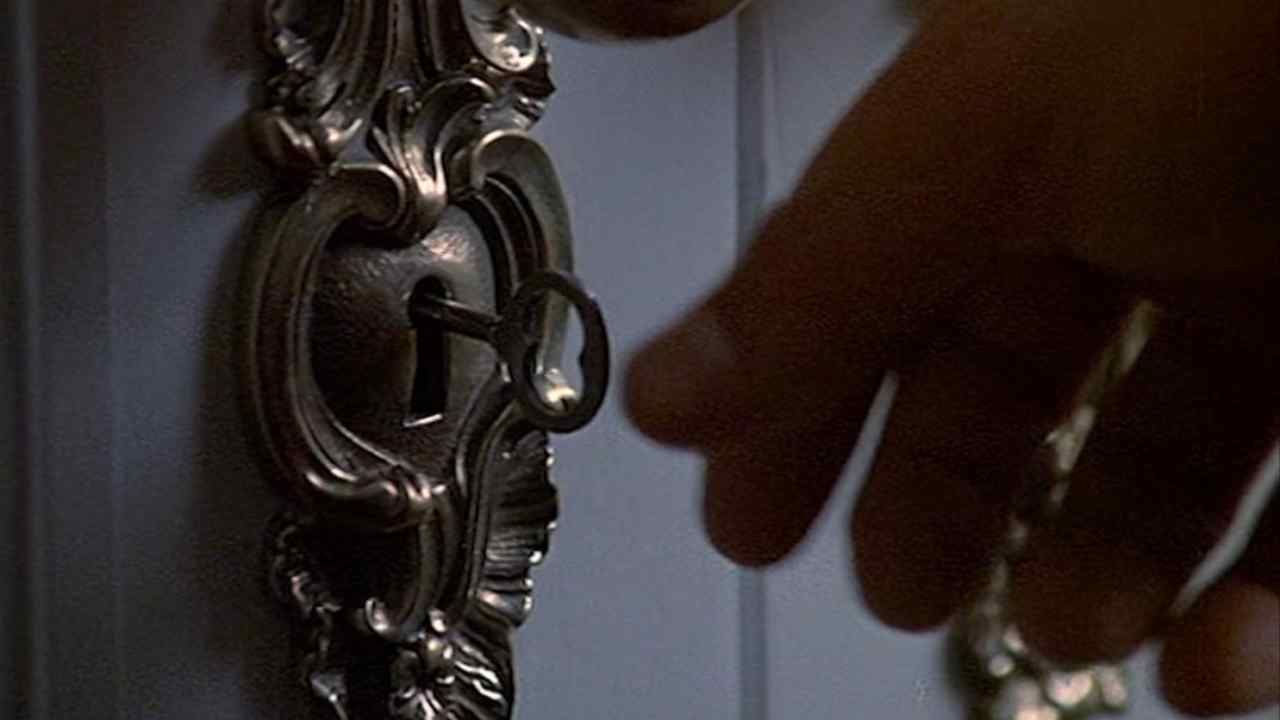 Close-up of a hand reaching for a key in an ornate lock