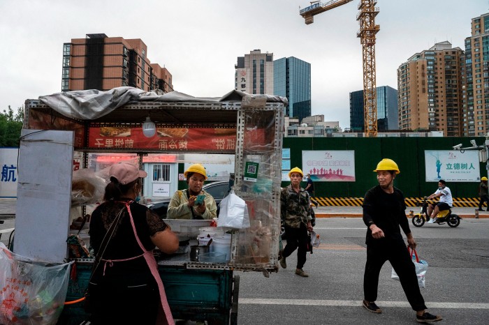 A construction worker buys food from a vendor as they and their colleagues leave a development project