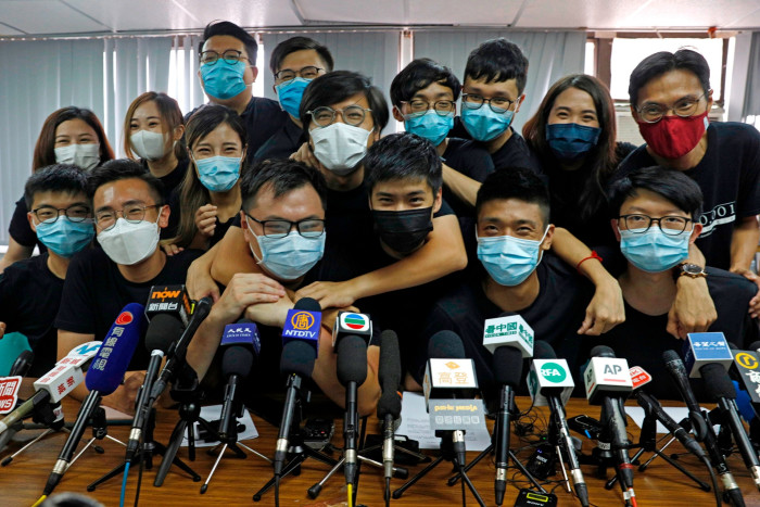 Pro-democracy activists who were elected during unofficial primaries, including Joshua Wong, far left, pose in front of microphones at a press conference in Hong Kong in 2020
