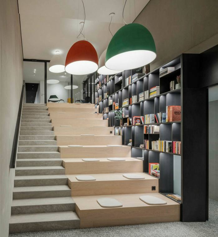 stairway wiith bookshelves on the side with large ceiling lights