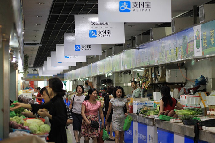 Shoppers in a food market in Wenzhou, China, with signs to say Alipay is accepted