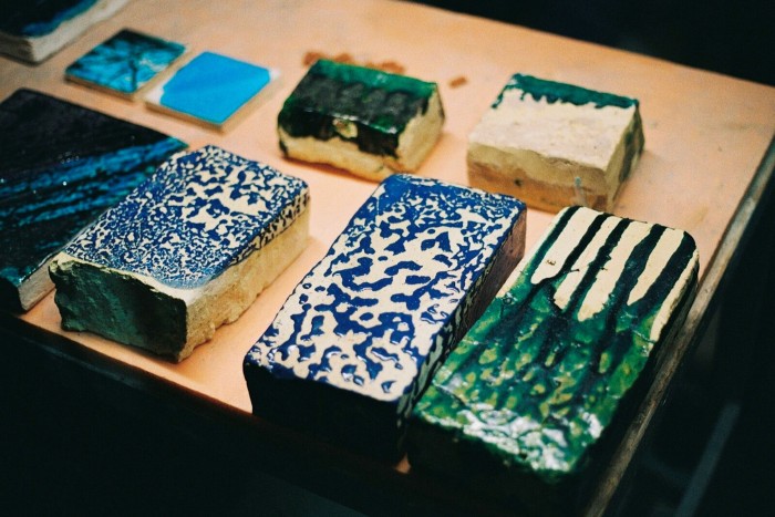 Colourful blue and green glazed bricks sit on a display table