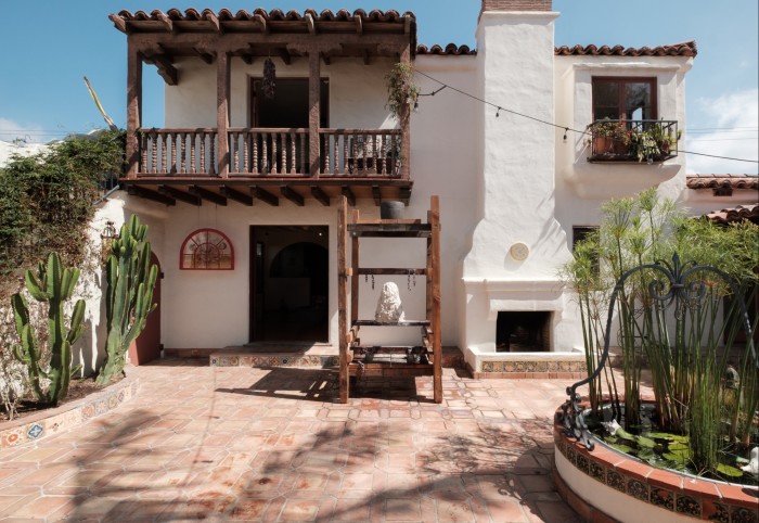 A wooden structure with a clay sculpture outside a Spanish-Colonial style house
