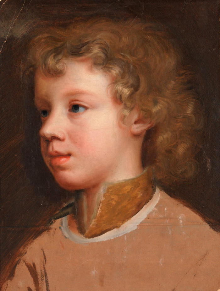 A portrait of a young boy with curly golden-brown hair. He is smiling gently and looking to one side