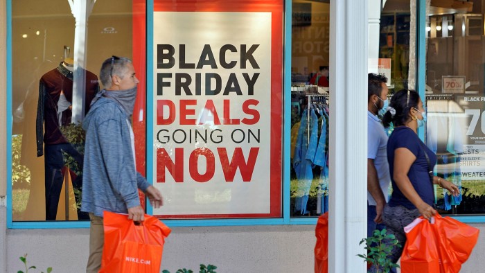 Shoppers pass a sign advertising Black Friday deals outside a store in Florida 