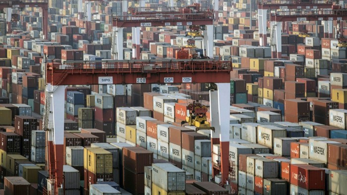 Stacks of shipping containers next to gantry cranes at a port in China