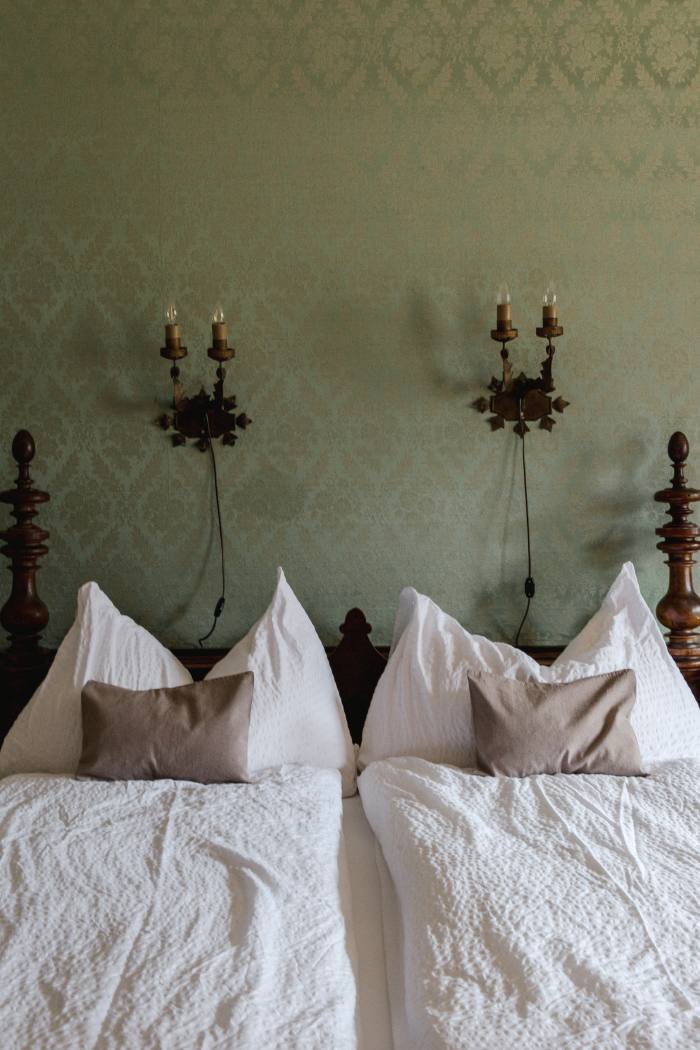 A bed in a Classic Room, with its pistachio-green silk-covered walls