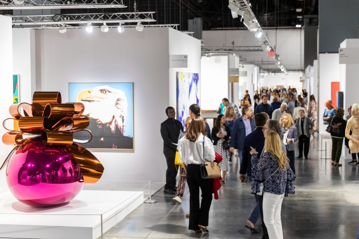 Smartly dressed people peruse the artworks on display inside a modern exhibition hall