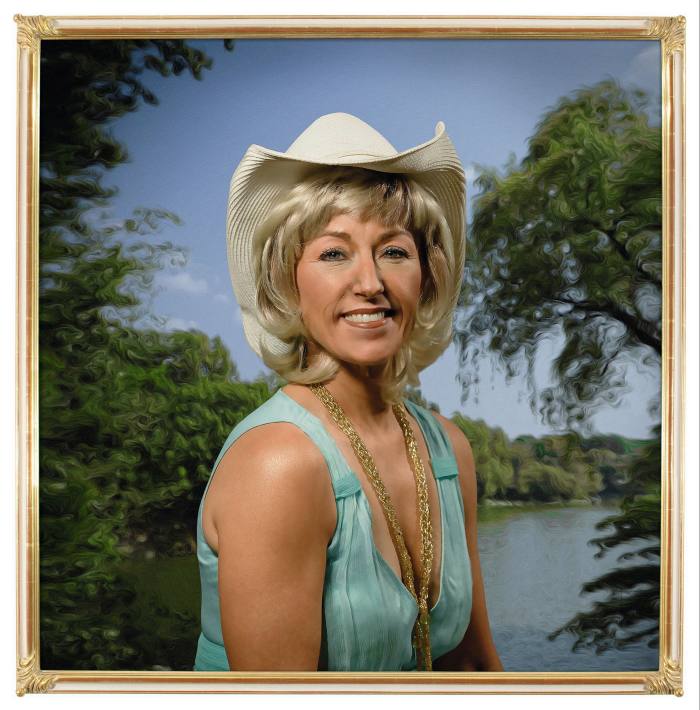 Photograph of a woman with big blonde hair and a stetson in front of a river and tree scene