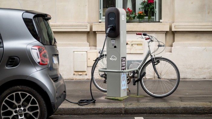 A Smart EQ Fortwo electric vehicle charges at a Belib’ station alongside a locked bicycle in Paris, France