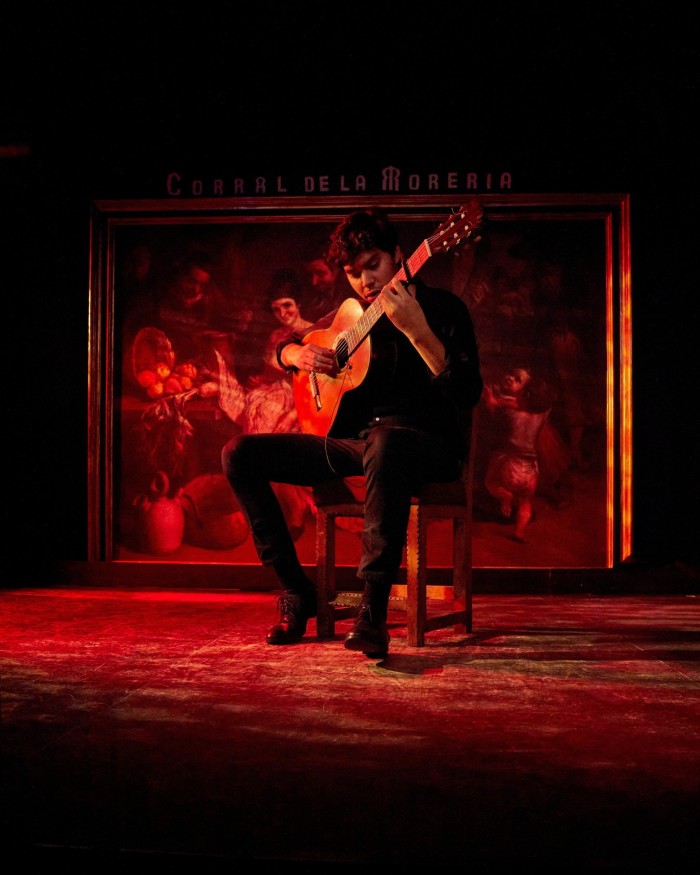 A red-lit man playing guitar on a stage in Madrid’s Corral de la Morería tablao