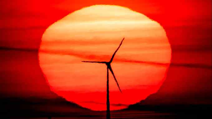 A wind turbine silhouetted a red rising sun