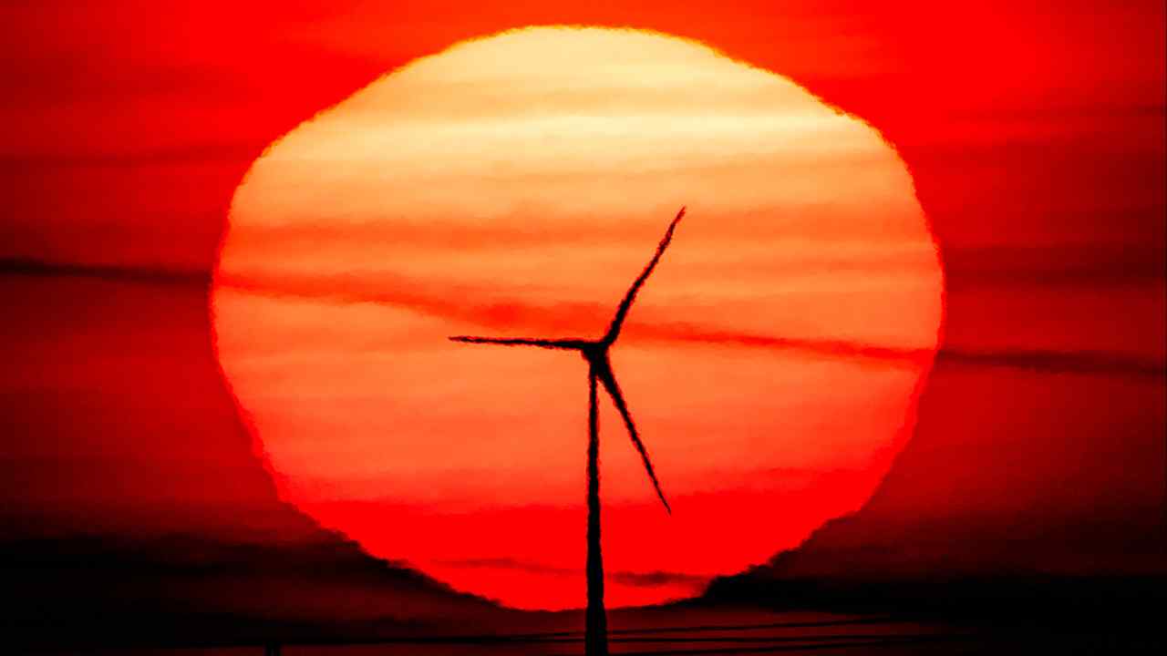 A wind turbine silhouetted a red rising sun